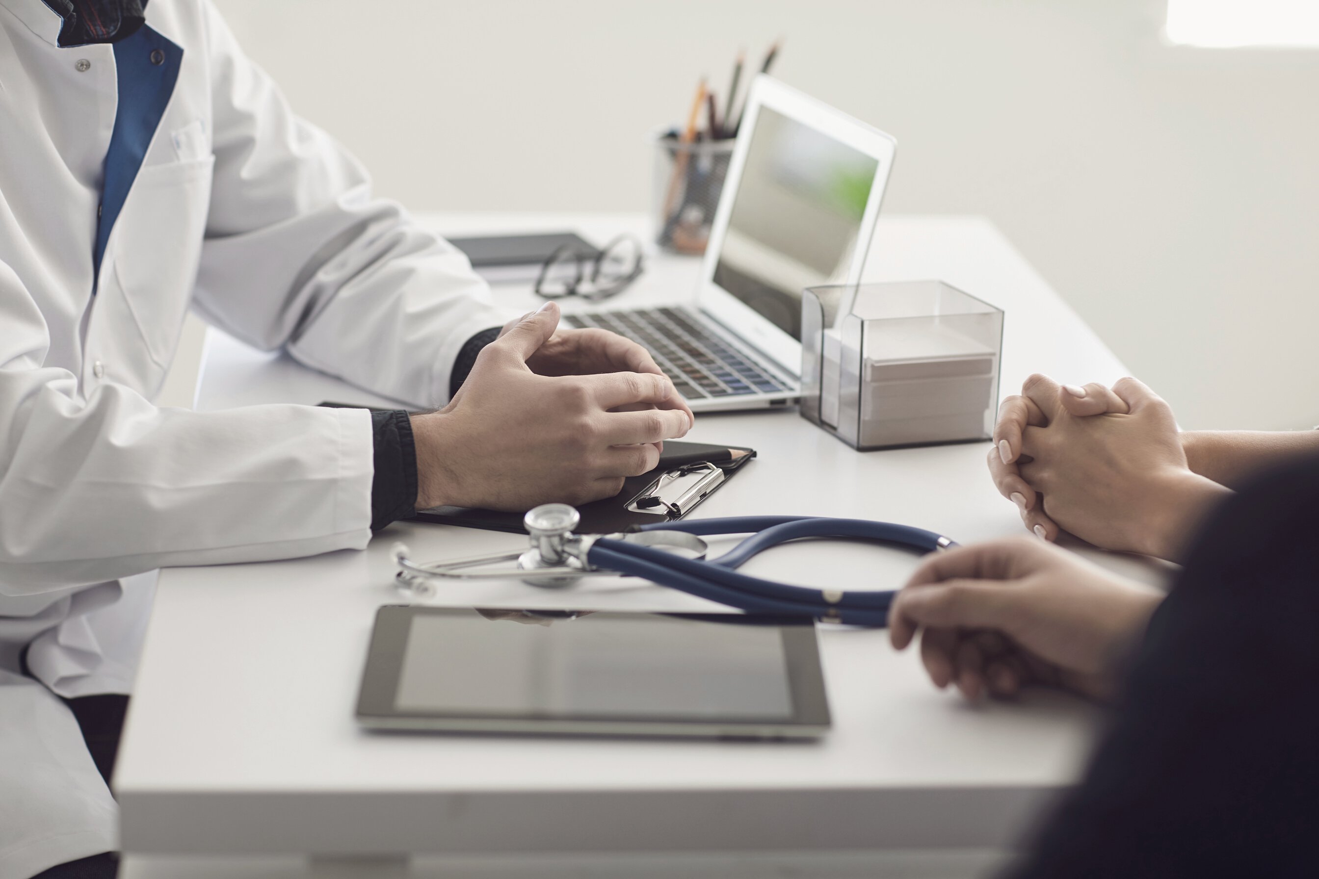 Confident Doctor and Couple Patient Sitting at the Table in Clinic Office. Family Doctor.